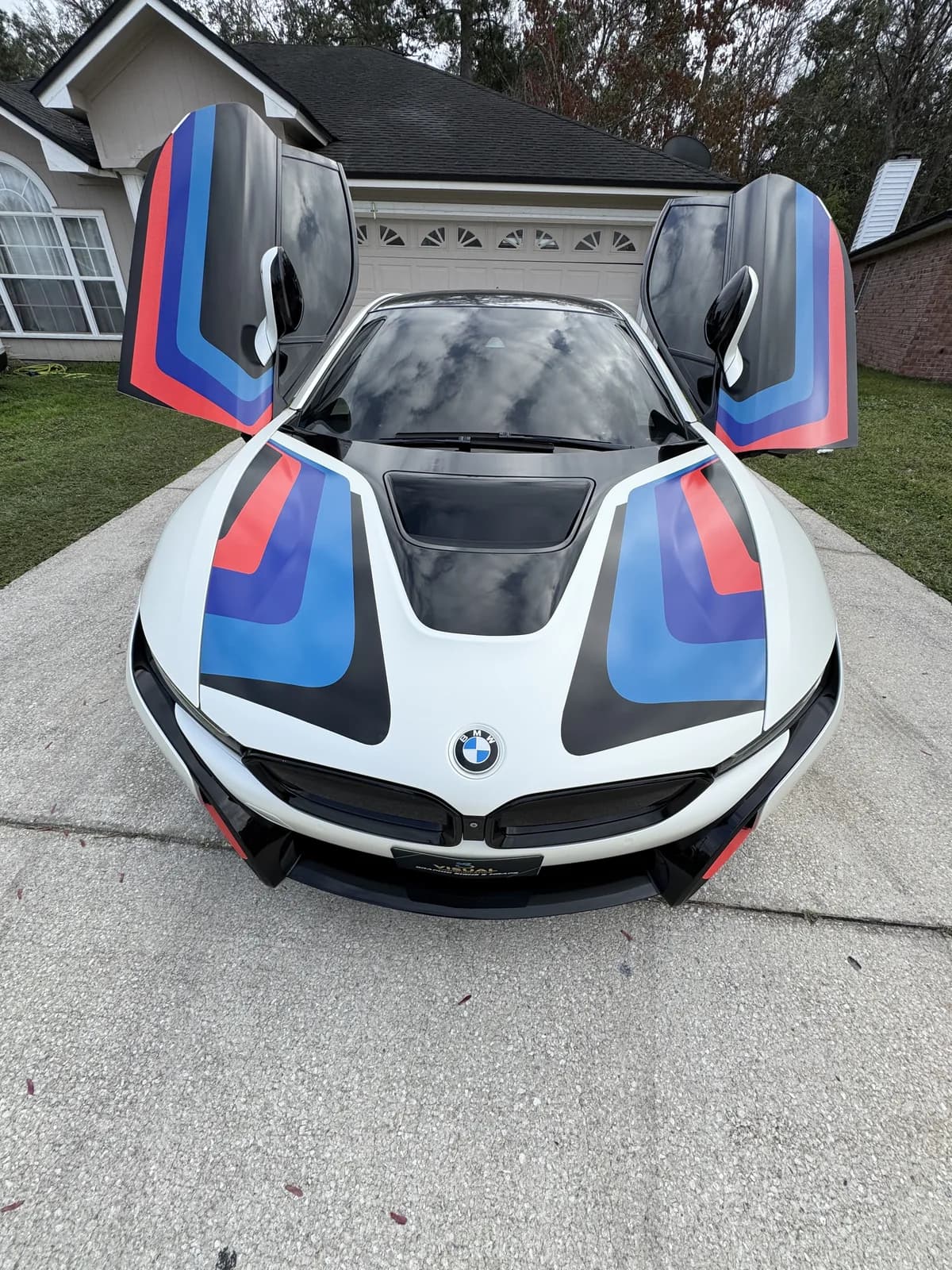 BMW i8 with the doors raised, wrapped in white with blue and red stripes