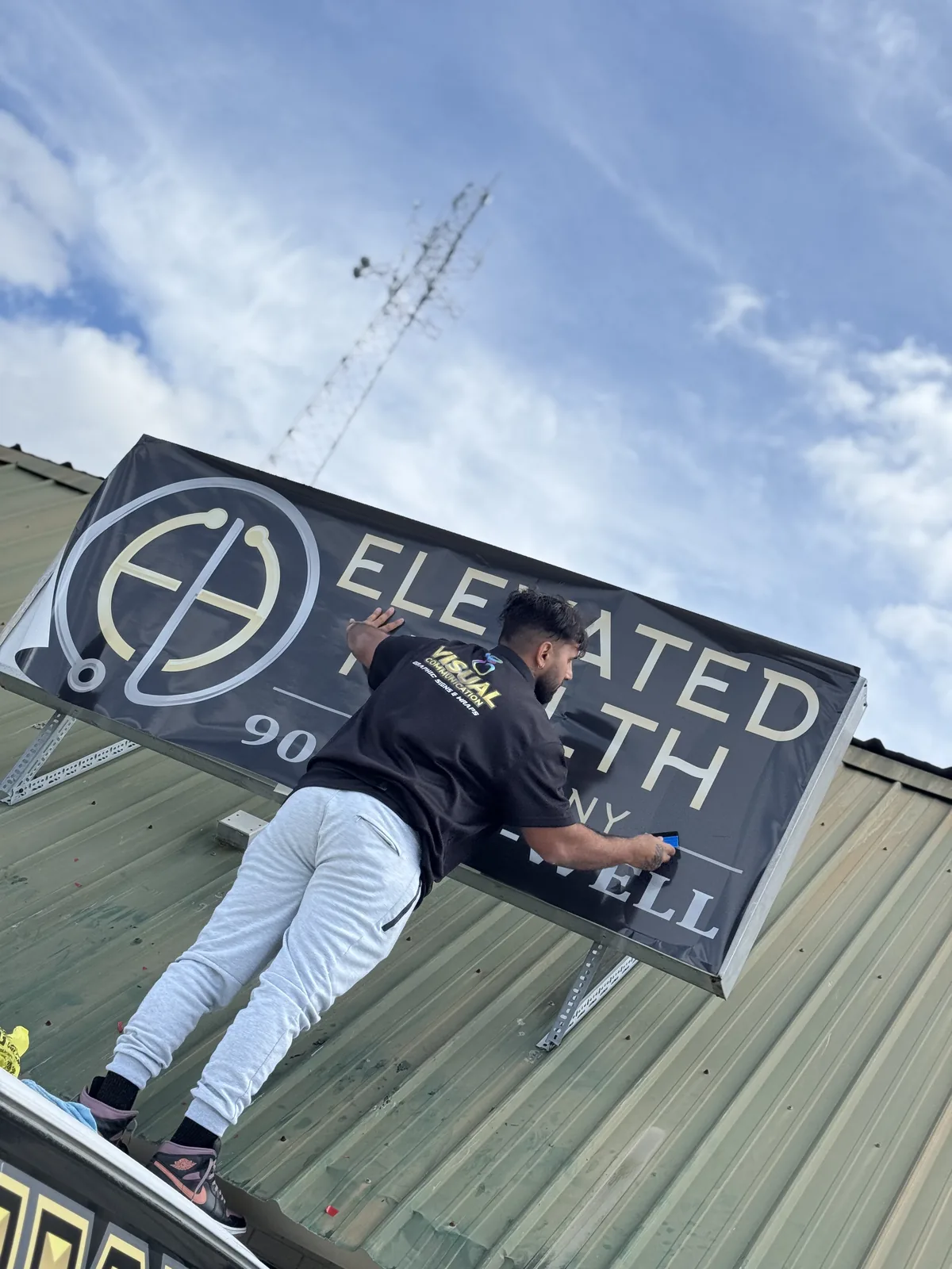 Sign being installed on the roofline of a health clinic