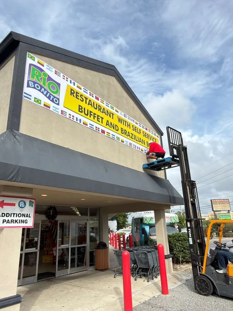 Building sign being installed above a Brazilian restaurant, lifted into place from a forklift