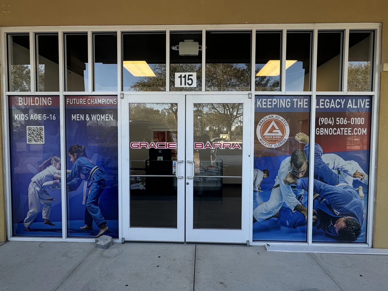 Martial arts gym storefront with printed window panels showing athletes
