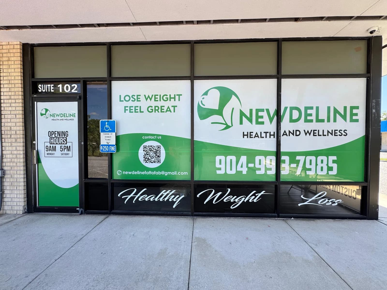 Health and wellness clinic storefront with printed window graphics and phone number